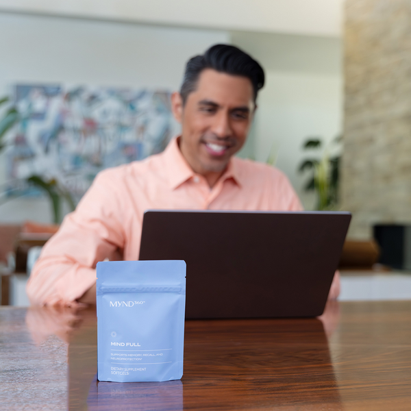 a photo of a gentlemen using laptop with mindful supplements on table