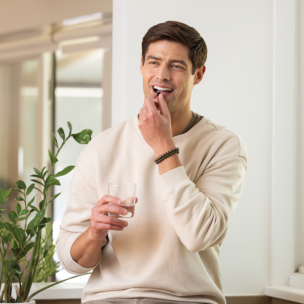 a photo of a man taking a pill of supplements